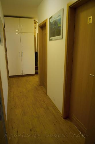 a hallway of an apartment with white cabinets and wood floors at Apartman DvacetSedm in Lipno nad Vltavou