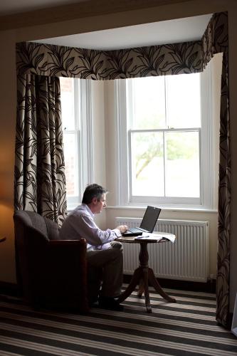 a man sitting at a table with a laptop at Links Country Park Hotel in Cromer