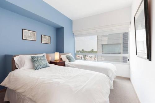 a blue bedroom with two beds and a window at Parque Sur Beautiful apartment 2 BE - 2 BA - 2 Parkings in Mexico City