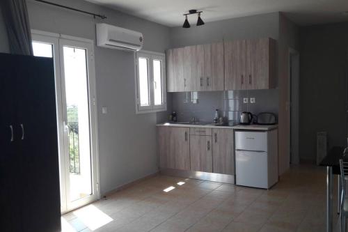 a kitchen with wooden cabinets and a white refrigerator at Rodanthy III in Katelios