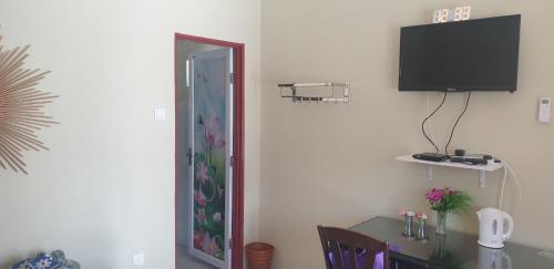 a room with a table and a television on a wall at MRI Residence - Homestay in Sg Buloh with Swimming Pool - No Pork&Alcohol Allowed in Bandar Puncak Alam