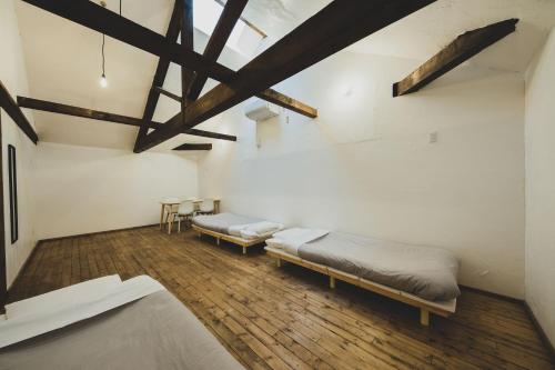 a room with three beds and a ceiling with beams at Otaru Tap Room & Hostel in Otaru