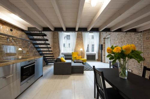 a kitchen and living room with a table and yellow chairs at Stylish Studio Apartment in the Heart of Riga in Riga