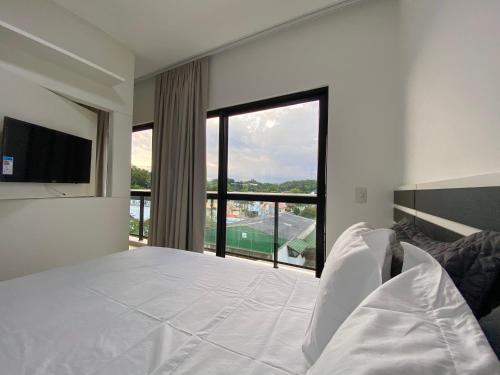 a bedroom with a large bed and a large window at MaxLoft - Apto novo Smart Tv, lavanderia in Joinville