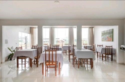 a dining room with white tables and wooden chairs at Nosso Hotel in Campo Grande