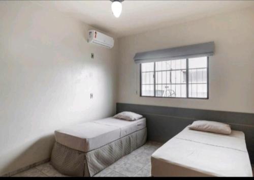 Habitación con 2 camas y ventana en Nosso Hotel, en Campo Grande