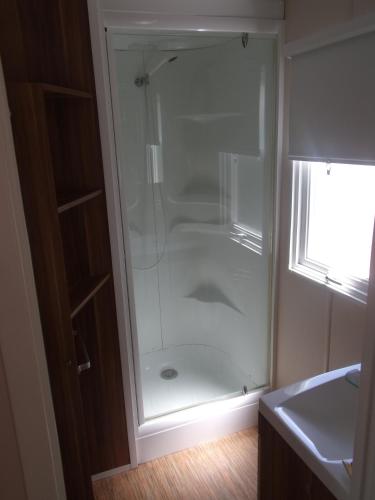 une douche avec une porte vitrée dans une salle de bain dans l'établissement Mobilhome des Tamaris, à La Cotinière