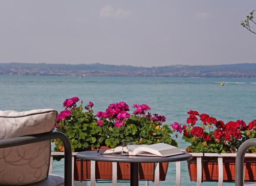 a table with a book on it next to flowers at Hotel Marconi in Sirmione