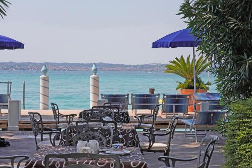 a group of tables and chairs with the ocean in the background at Hotel Marconi in Sirmione