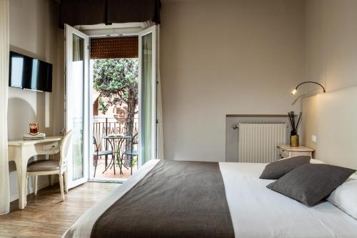 a bedroom with a bed and a desk and a balcony at Hotel Marconi in Sirmione