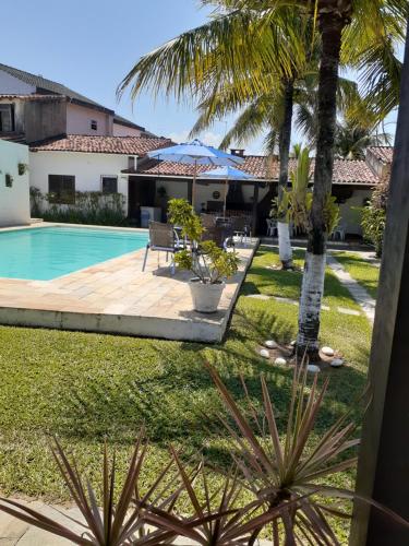 einen Hinterhof mit einem Pool und Palmen in der Unterkunft casa de praia Itaúna saquarema in Saquarema