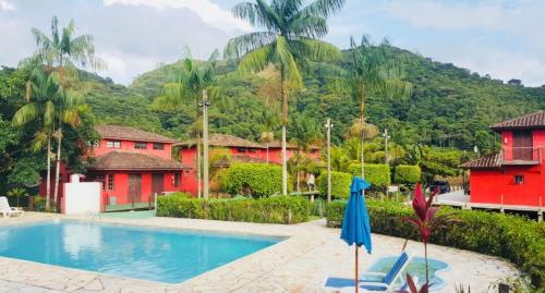a resort with a swimming pool and mountains in the background at Chales Terra Pura in Camburi