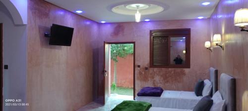 a living room with a couch and a tv on a wall at Hôtel Ajil Cascades D'ouzoud in Ouzoud