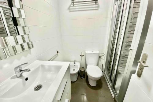 ein weißes Bad mit einem WC und einem Waschbecken in der Unterkunft Vacation Home Studio Los Cristianos in Arona