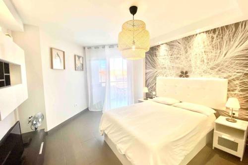 ein Schlafzimmer mit einem weißen Bett und einer Hängeleuchte in der Unterkunft Vacation Home Studio Los Cristianos in Arona