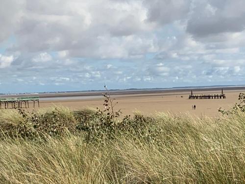 a beach with a pier and people on the sand at Beach Snug in Lytham St Annes