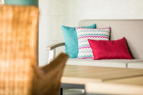 a couch with two colorful pillows on it at Amadores Beach Apartments in Mogán