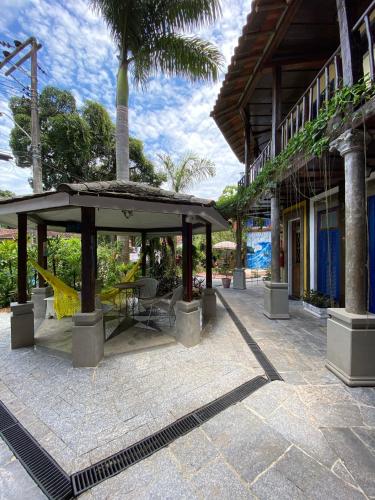 a pavilion with a table and chairs in front of a building at Vila Pequeá Pousada Ilhabela in Ilhabela
