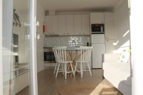 a kitchen with white cabinets and a table and chairs at Recantus Comporta in Comporta
