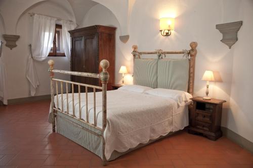 a bedroom with a bed and a dresser and lamp at Castello Vicchiomaggio in Greve in Chianti