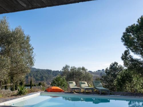 een zwembad met 4 stoelen en een parasol bij Villa des Cathares in Carcassonne