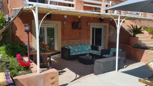 une terrasse avec un canapé et un parasol dans l'établissement Escapades en provence, à Saint-Zacharie
