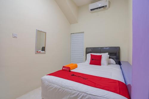 RedDoorz near Trans Studio Bandung 3 في باندونغ: غرفة نوم مع سرير كبير مع الوسائد الحمراء والبرتقالية