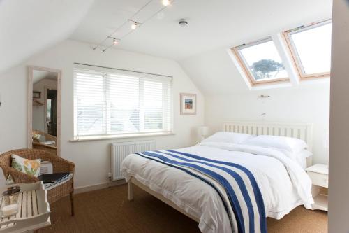 a white bedroom with a bed and two windows at Nearwater in Saint Mawes