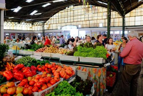 a group of people in a market with fruits and vegetables at Beachfront Apartment Nazaré in Nazaré