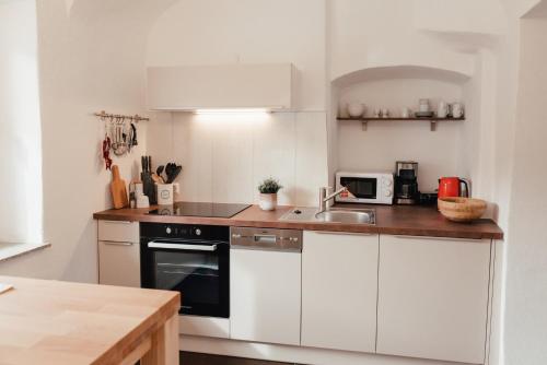 a kitchen with white cabinets and a sink at Smarthotel Völkermarkt in Völkermarkt