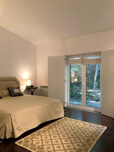 a bedroom with a bed and a large window at Casa do Galo / Galo House in Vimioso