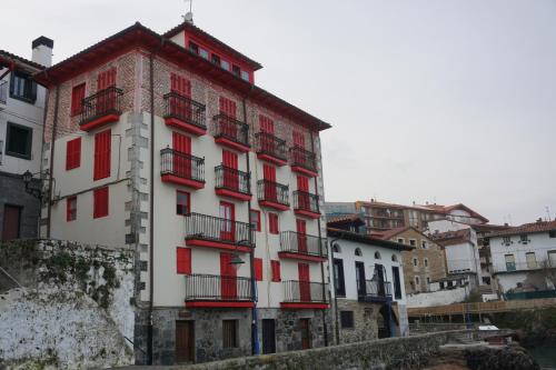 a tall white building with red shuttered windows at ATICO TORRONTERO in Mundaka