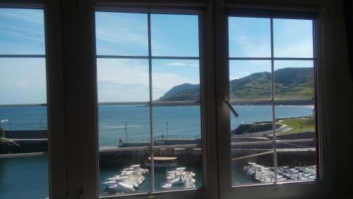 a window with a view of the water and a harbor at ATICO TORRONTERO in Mundaka