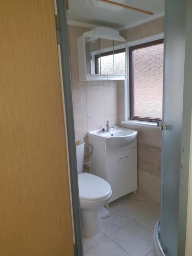 La salle de bains est pourvue de toilettes, d'un lavabo et d'une fenêtre. dans l'établissement CHATKY JANA, à Doksy