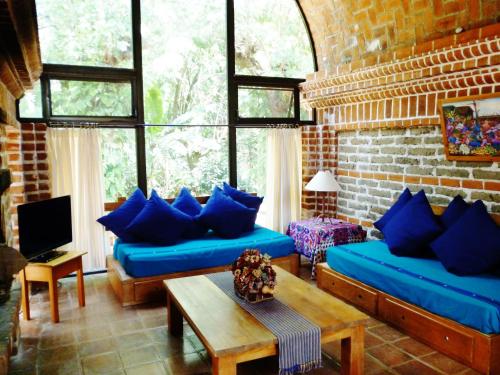 a living room with blue couches and a brick wall at Hotel San Buenaventura de Atitlán in Panajachel