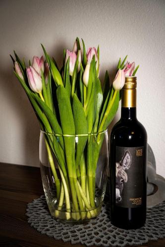 a vase of pink tulips next to a bottle of wine at Landhaus Steinmüller in Längenfeld