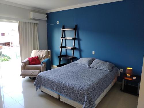 1 dormitorio con una pared azul, 1 cama y 1 silla en Casa em Ingleses, en Florianópolis