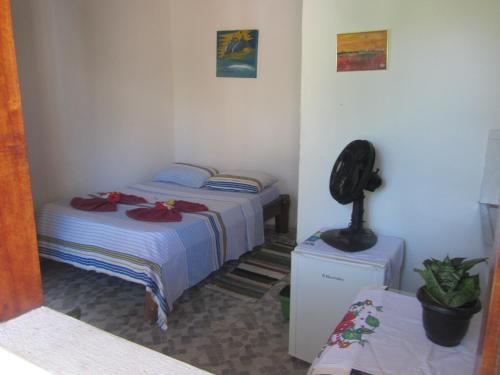 a small room with two beds and a fan at Casa do Miguel in Itacaré