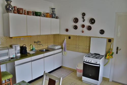 a kitchen with white cabinets and a stove top oven at Pesti Vendégház Zalalövő in Zalalövő