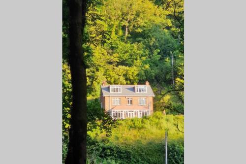 a large house on a hill with trees at The Eaves in Lynton, Exmoor, Devon in Lynton