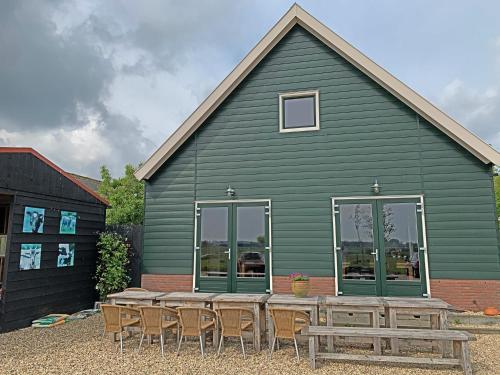 a green building with a picnic table and chairs at Christinahoeve Logies in Boskoop