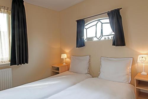 2 Betten in einem Zimmer mit 2 Fenstern in der Unterkunft Christinahoeve Hooiberg #5 in Boskoop