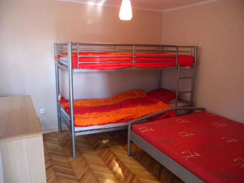 Habitación con 2 literas y sábanas rojas. en Holiday home in Balatonmariafürdo 26831 en Balatonmáriafürdő