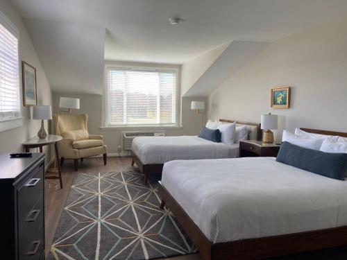 una habitación de hotel con 2 camas y una silla en Tilghman Island Inn, en Tilghman Island