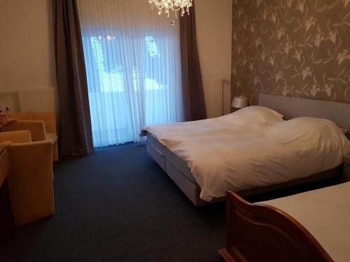 a bedroom with a bed and a window with a chandelier at Berghotel Natura Bed & Breakfast in Winterberg