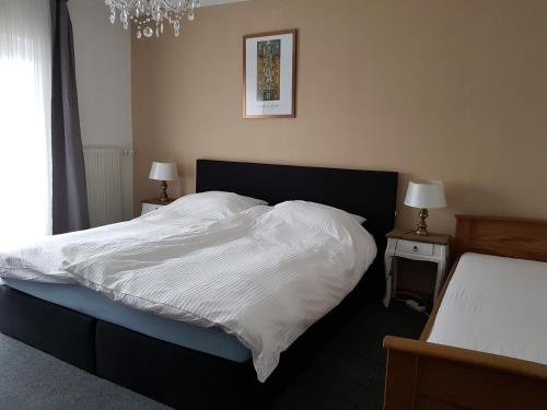 a bedroom with a bed with white sheets and a chandelier at Berghotel Natura Bed & Breakfast in Winterberg
