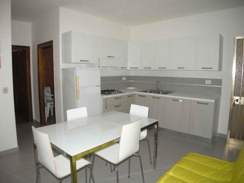 una cucina bianca con tavolo e sedie bianche di Apartments in Rosolina Mare 25011 a Rosolina Mare