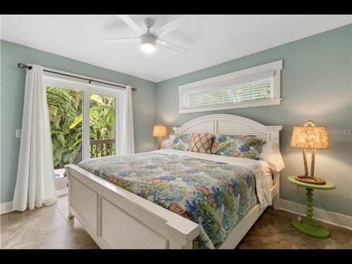 a bedroom with a bed and a window and a fan at AMI/Holmes Beach - 3/2 Home - Private Heated Pool and Yard - walk to beach in Holmes Beach