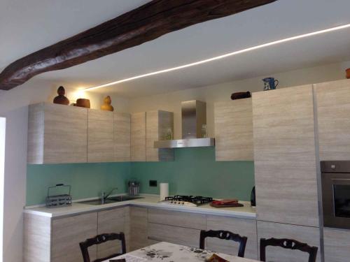 una cocina con armarios de madera y una mesa con sillas. en Apartment Madonna Del Sasso/Piemont 22865, en Madonna del Sasso