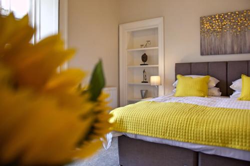 a bedroom with a bed with a yellow bedspread at Wallace View Apartment in Stirling